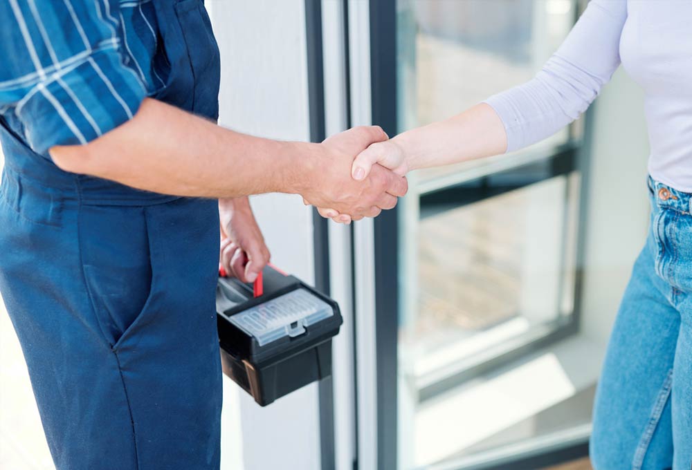 technician with toolbox shaking hands with a homeowner