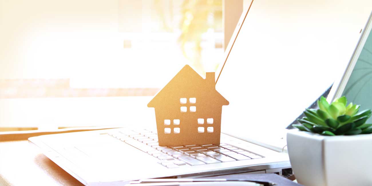 a cutout of a house sitting on a laptop in front of an open window with the sun shining through